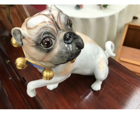 A ceramic painted pug with collar and bell