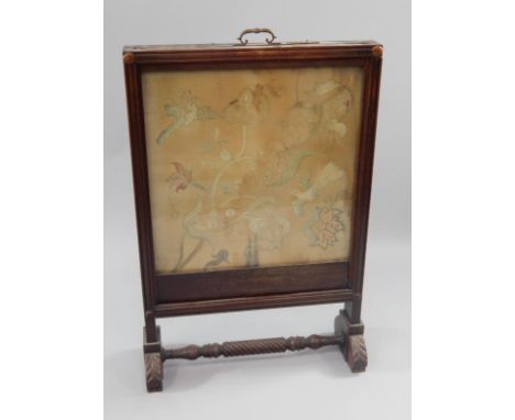 A Regency mahogany fire screen, having two glazed panels with needlework decoration, one with trailing foliage and birds and 