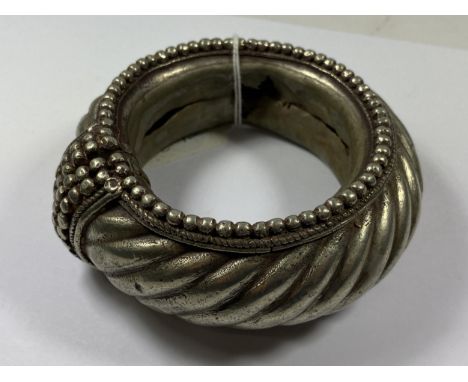 A VINTAGE TRIBAL ORNATE BANGLE, TESTED SILVER 