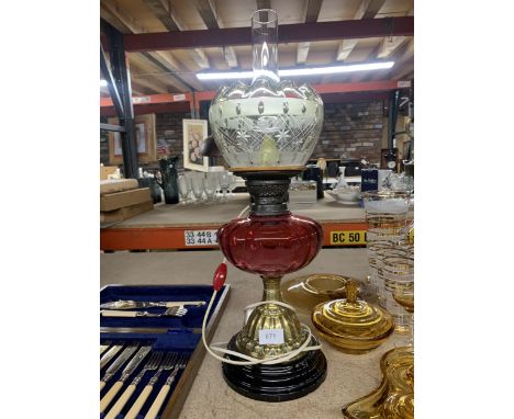 A CONVERTED OIL LAMP WITH BRASS BASE, CRANBERRY GLASS RESERVOIR, GLASS SHAD AND FUNNEL 