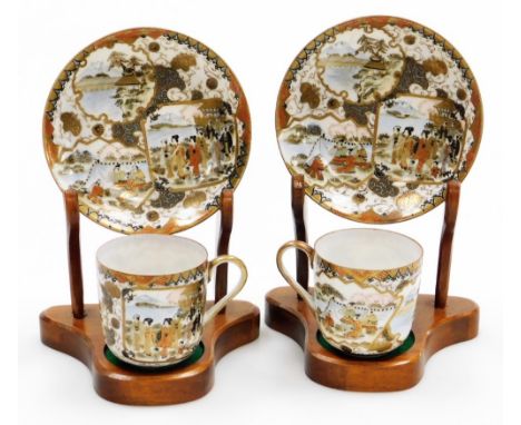 A pair of Japanese Meiji period Kutani porcelain coffee cups and saucers, decorated with reserves of figures and landscapes, 