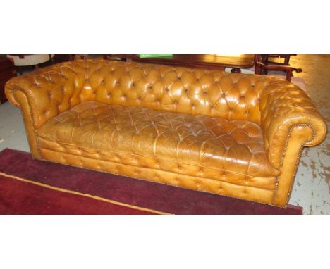 CHESTERFIELD SOFA, in old buttoned tan leather on castors, 217cm x 95cm. (with faults)