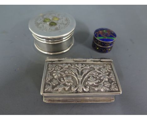 A white metal snuff box in the form of a book with embossed foliate decoration, a circular Indian silver lidded box and an en
