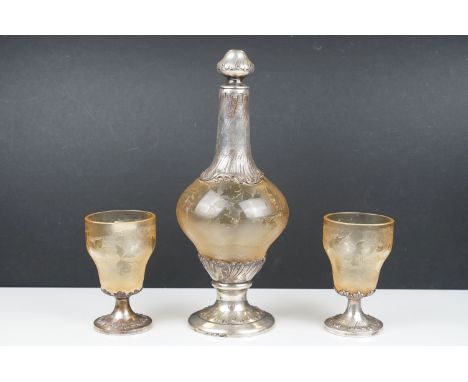 A silver plated and etched glass decanter with two similar glasses. 