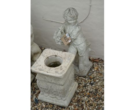 A garden statue of a boy standing by a tree stump, holding a basket of fruit, on separate plinth, approx 1m 16cm in height. 