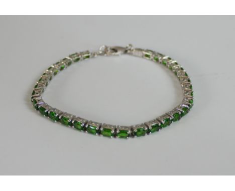 A boxed silver green stone set tennis bracelet with secure lobster clasp. Stamped 925. L.20cm 