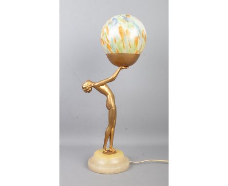 An Art Deco style figural table lamp depicting a woman with outstretched arms holding a spherical shade. Raised on turned ste