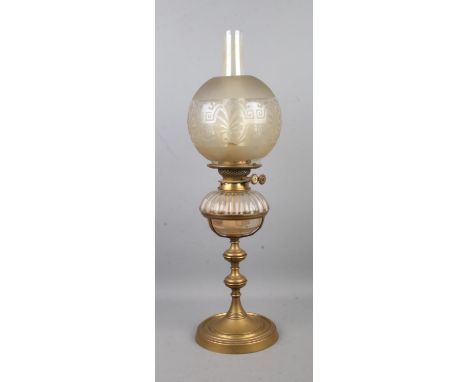 A brass and glass oil lamp, produced by Hinks &amp; Sons, with frosted shade above glass reservoir. Raised on turned base, st