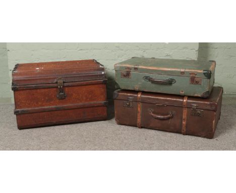 A large collection of vintage travel trunks and suitcases including a wood bound steamer trunk and a tin metal example  