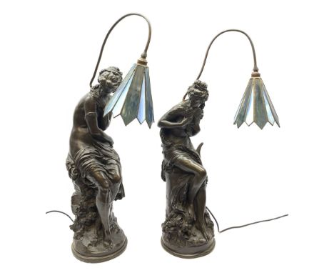A pair of bronzed table lamps, modelled as female figures, with dark and light blue leaded glass shades, overall H79cm. Click