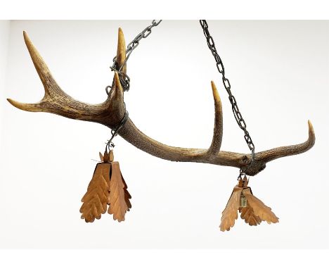 An antler light fitting, the single antler supporting two copper light shades modelled as oak leaves, overall H70cmClick here