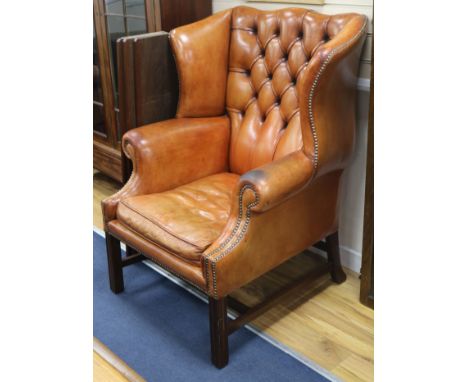 A pair of button back leather wing armchairs