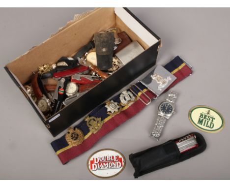 A box of collectables to include quartz wristwatches, brass beer labels, military badges, multi tools etc.