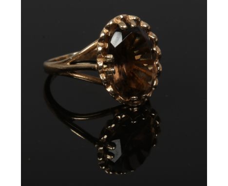 A vintage 9ct gold and smokey quartz cocktail ring, set with a faceted ovoid stone with a crimped skirt, size M.