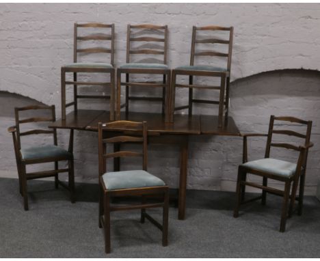 An Ercol dark oak draw leaf dining table along with six matching ladder back dining chairs including two carvers.