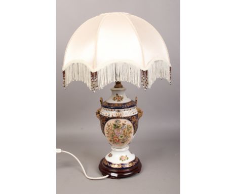 A pottery table lamp with gilt decoration and cream silk shade raised on turned wood base.