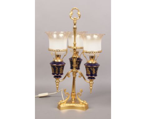 A gilt metal three branch table lamp, each branch formed as an oil lamp with blue pottery font decorated with Neo classical f