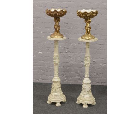 A pair of painted and distressed composite torcheres along with a pair of gilded ceramic bowls raised on figural bases formed