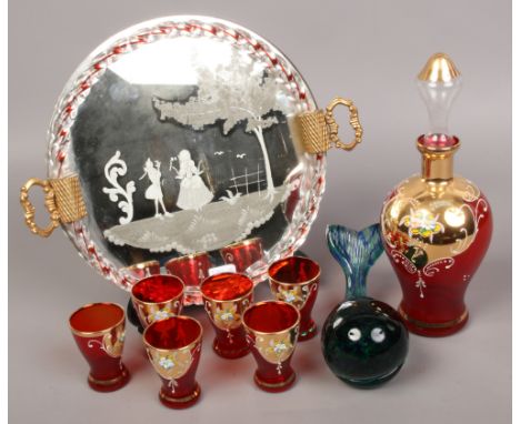 A gilded ruby glass liquor set with decanter and six vessels on mirror and etched twin handle tray, along with a Wedgwood gla