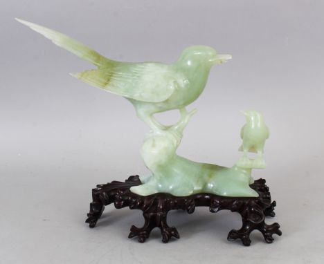 A 20TH CENTURY CHINESE CELADON GREEN JADE CARVING OF TWO BIRDS PERCHED ON ROCKWORK, together with a fitted wood stand and als