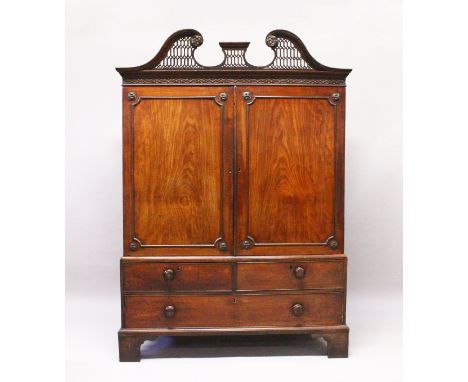 A GEORGE III MAHOGANY LINEN PRESS, with carved and pierced swan neck pediment, a pair of doors enclosing four sliding shelves