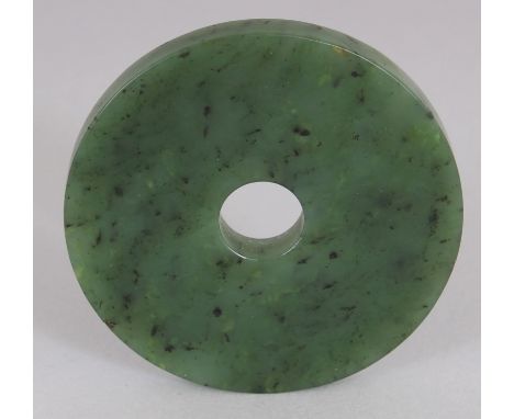 A GOOD CHINESE SPINACH GREEN NEPHRITE JADE BI DISC, possibly Han Dynasty, the stone with paler and with black inclusions, 2.3