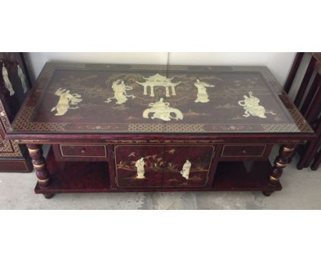 A Chinese red lacquer coffee table with storage & glass top with applied mother of pearl figures and gilt painted decoration.