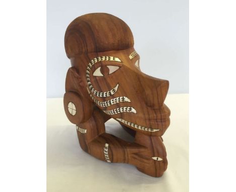 A Soloman Islands 'Nguzu Nguzu' carved wooden replica of the prow figurehead of a war canoe. Inlaid with mother of pearl. 26c