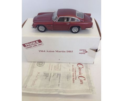 A boxed Danbury Mint 1:24 scale 1964 Aston Martin DB5 in dubonnet maroon colour with certificate. In excellent condition.