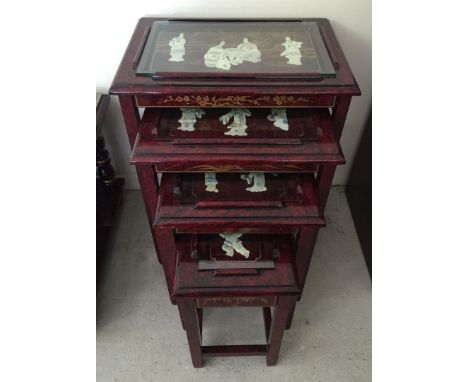 A Chinese nest of 4 red lacquer tables with glass tops with applied mother of pearl figures and gilt painted decoration.