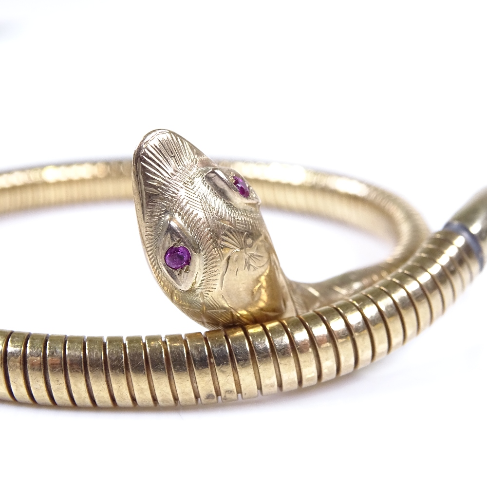 A 9ct gold snake bangle, with ruby eyes and textured engraved head