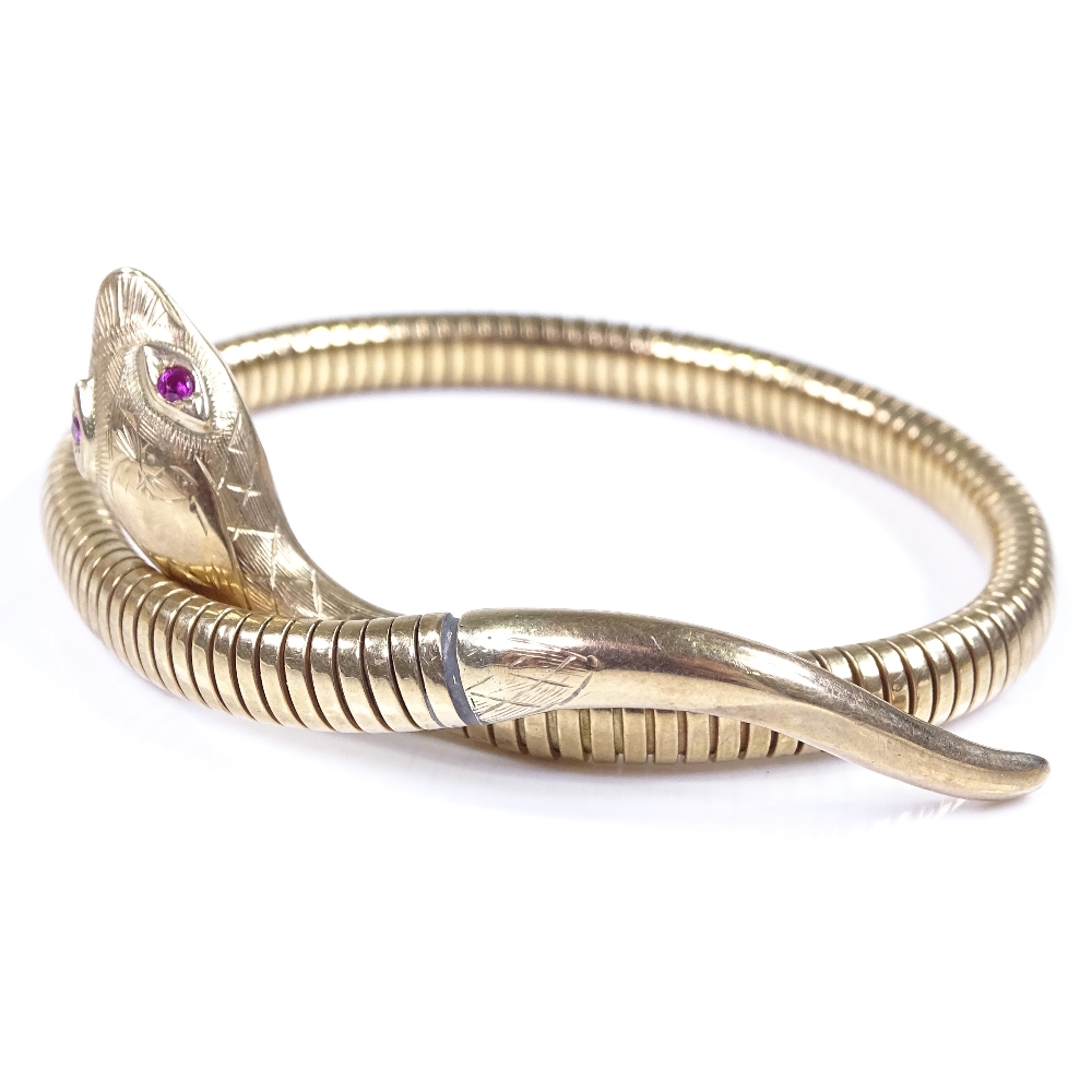 A 9ct gold snake bangle, with ruby eyes and textured engraved head