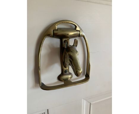 A brass door knocker in the form of a horse's head within a stirrup. (Dimensions: Height 12cm, width 11cm.)(Height 12cm, widt