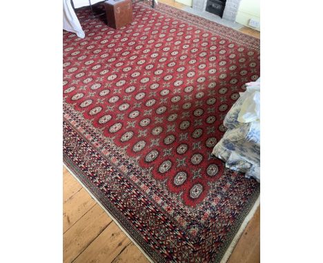 A Pakistan carpet, the red ground with multiple rows of guls. (Dimensions: 405cm x 308cm)(405cm x 308cm)