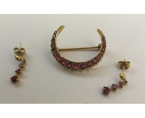 A 9 carat ruby crescent-shaped brooch together with matching earrings. Approx. 5 grams. Est. £30 - £50.