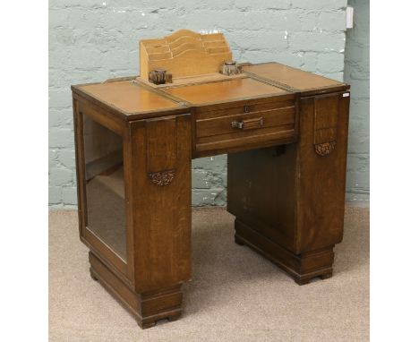 An oak Art Deco metamorphic writing desk by Maco. With glazed bookends pedestals, cut glass ink wells and letter rack.