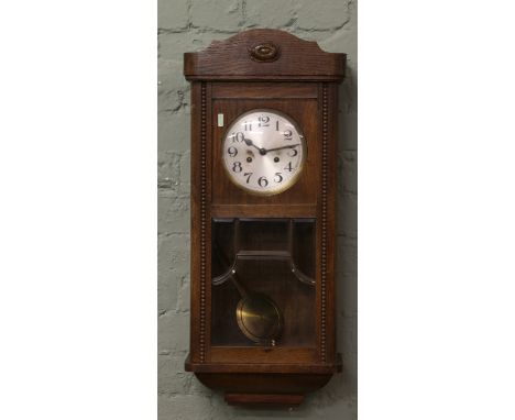 An oak cased eight day wall clock striking on a gong.