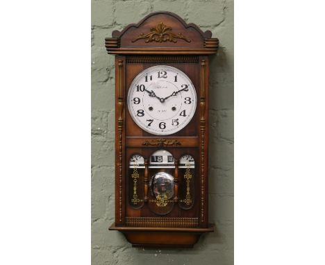 A C20th mahogany cased thirty one day wall clock incorporating day and date calender and chiming on a coiled gong.