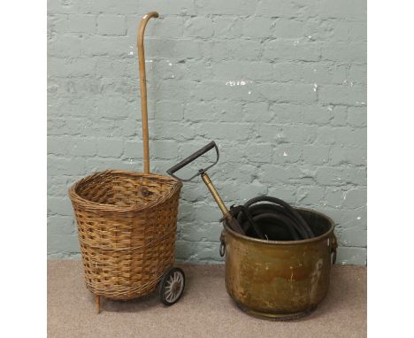 A brass log box with lion mask handles, vintage hand pump and a shopping basket on wheels.