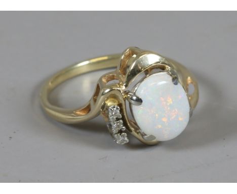 A gold ring scroll set with an opal and three diamonds, size R.