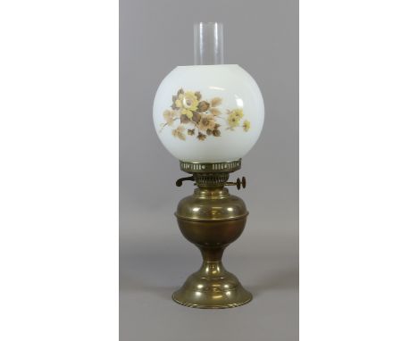An early C20th brass oil lamp with glass shade and chimney.