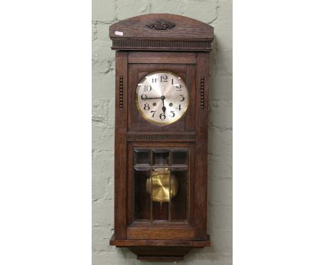 An early C20th oak cased wall clock with Arabic numeral dial enclosing twin train movement.