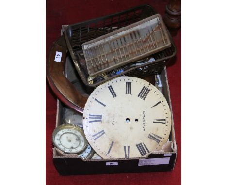 A box of clock parts including dials, pendulums along with tools.