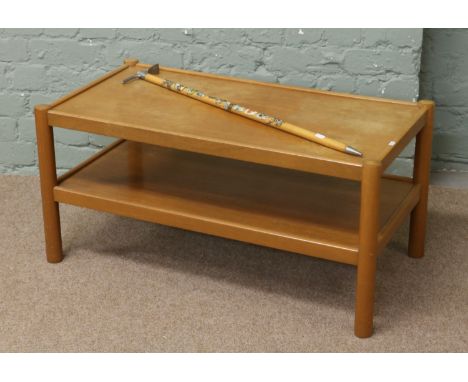 A mid C20th beech two tier coffee table with souvenir model of an ice axe with badger.