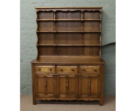 An Ercol carved Welsh dresser with four tier delft rack and panelled cupboards.