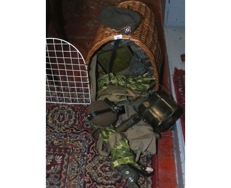 A wicker work pet carrier containing army surplus to include gators, torch, belt, drinks bottle etc.