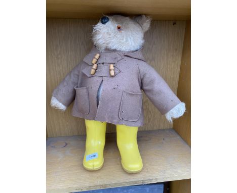 A VINTAGE TEDDY BEAR WEARING A RAIN COAT AND YELLOW WELLINGTON BOOTS 