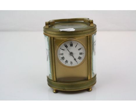An oval brass cased carriage clock with white enamel dial, complete with key.