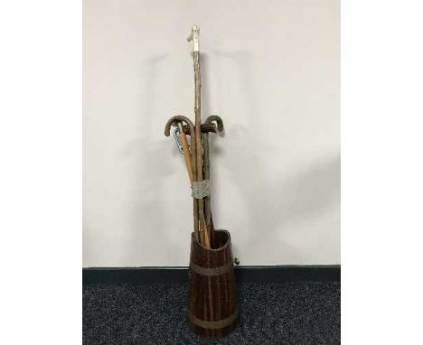 A wooden copper bound stick stand and bundle of walking sticks and a shooting stick 