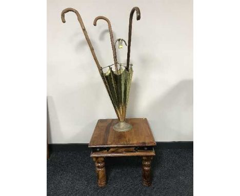 A brass stick stand in the form of an upturned umbrella containing three walking sticks and a pine coffee table 